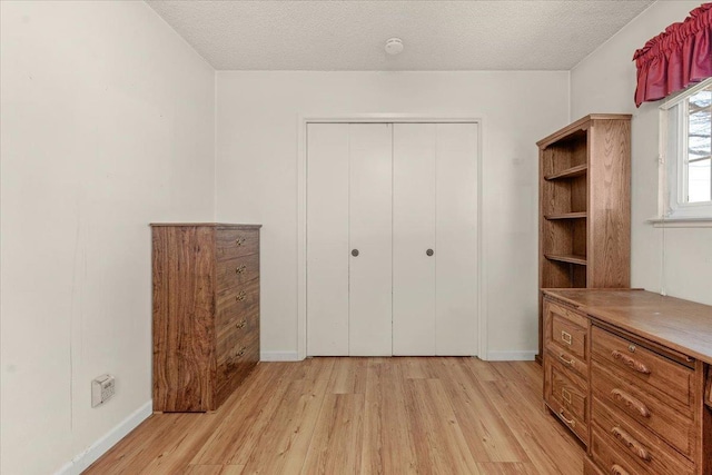 unfurnished bedroom with light hardwood / wood-style floors, a closet, and a textured ceiling