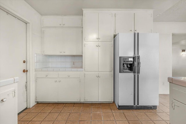 kitchen featuring white cabinetry, decorative backsplash, and white refrigerator with ice dispenser