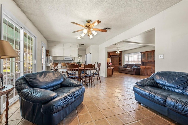 tiled living room with ceiling fan and a textured ceiling