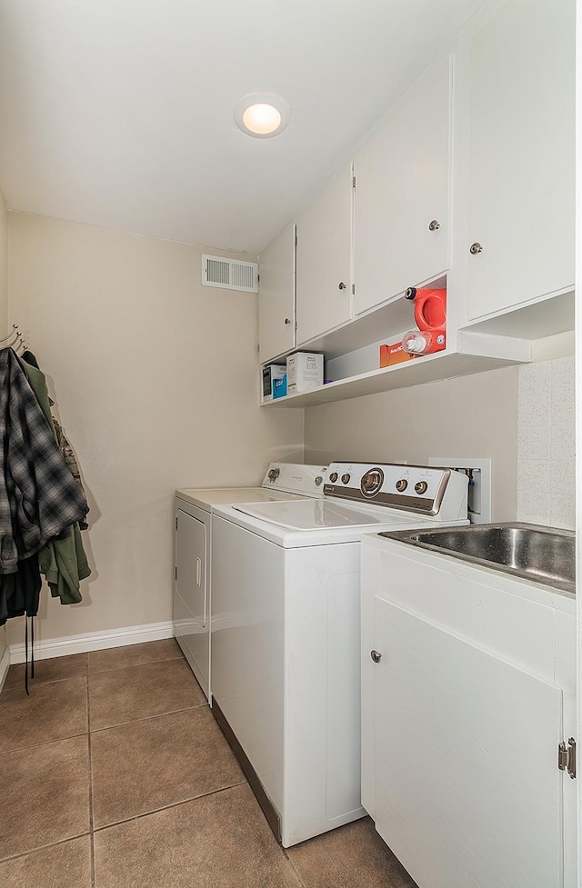 clothes washing area featuring separate washer and dryer, light tile patterned floors, and cabinets