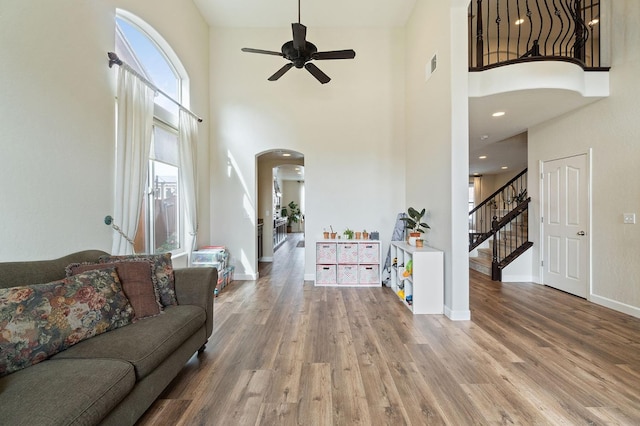 living room featuring hardwood / wood-style flooring, a towering ceiling, and ceiling fan