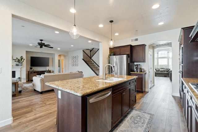 kitchen featuring sink, stainless steel appliances, dark brown cabinetry, an island with sink, and decorative light fixtures