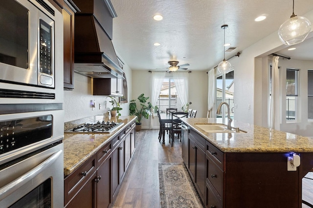 kitchen featuring premium range hood, decorative light fixtures, sink, dark hardwood / wood-style flooring, and stainless steel appliances