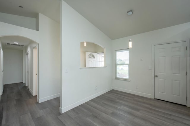 interior space featuring baseboards, visible vents, wood finished floors, and arched walkways