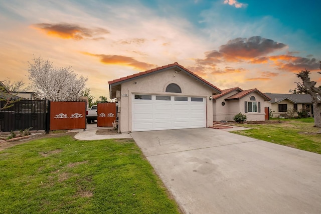 mediterranean / spanish home with stucco siding, a front yard, a gate, and an attached garage