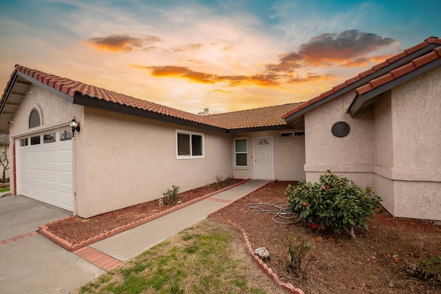 exterior space with stucco siding, an attached garage, and a tiled roof