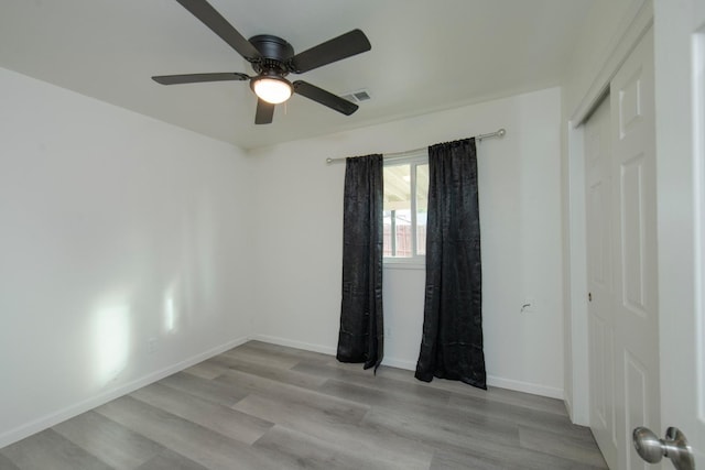 unfurnished room featuring a ceiling fan, visible vents, baseboards, and light wood finished floors