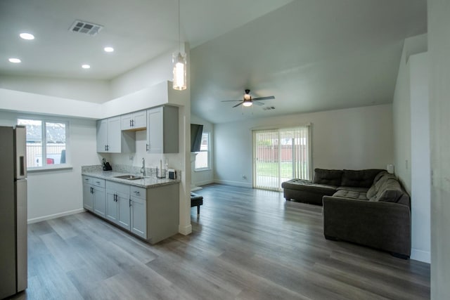 kitchen featuring open floor plan, visible vents, a healthy amount of sunlight, stainless steel fridge, and a sink