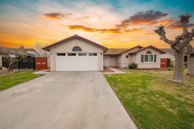 mediterranean / spanish house with fence, driveway, a garage, a front lawn, and stucco siding