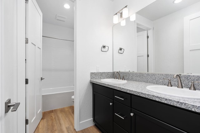 full bathroom with wood-type flooring,  shower combination, vanity, and toilet