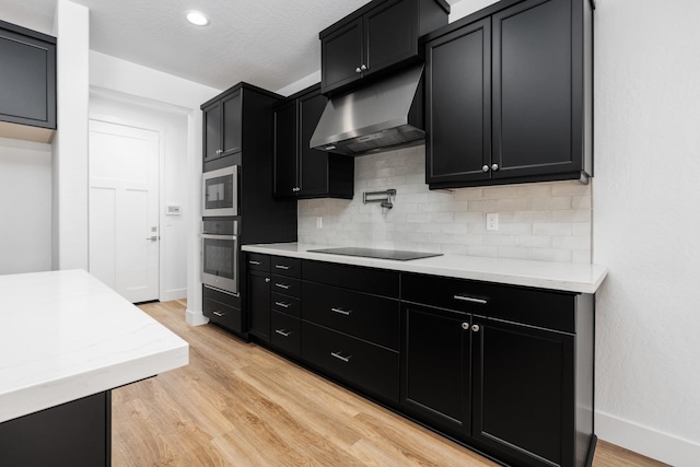 kitchen with stainless steel appliances, light hardwood / wood-style flooring, decorative backsplash, and range hood