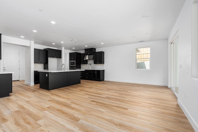 kitchen featuring backsplash, light hardwood / wood-style flooring, and an island with sink