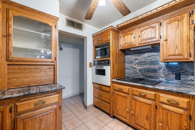 kitchen with tasteful backsplash, light tile patterned floors, ceiling fan, black electric stovetop, and white oven