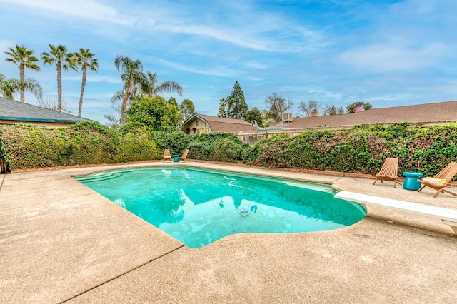 view of pool with a diving board and a patio