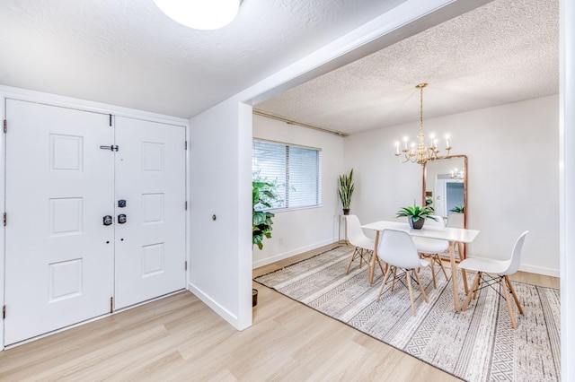 entryway featuring an inviting chandelier, light hardwood / wood-style flooring, and a textured ceiling