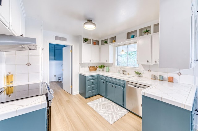 kitchen featuring appliances with stainless steel finishes, blue cabinets, sink, white cabinets, and light wood-type flooring