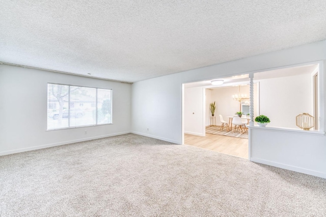 carpeted empty room featuring an inviting chandelier and a textured ceiling