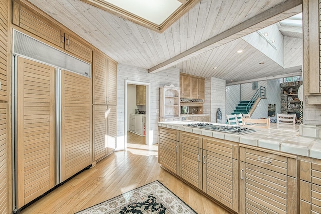 kitchen with light hardwood / wood-style flooring, beam ceiling, tile counters, wooden ceiling, and stainless steel gas stovetop