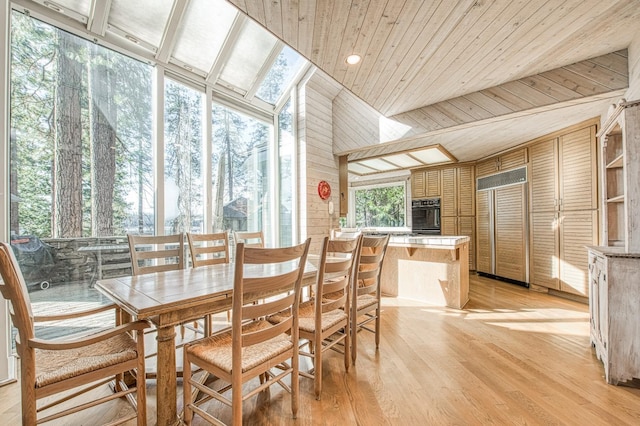 dining area featuring vaulted ceiling, wooden ceiling, light hardwood / wood-style floors, and wood walls