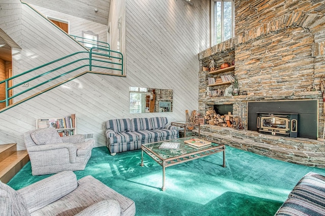 carpeted living room featuring a towering ceiling, a wood stove, and wooden walls