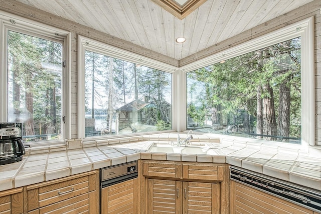 interior space with wood ceiling, tile counters, dishwashing machine, and sink