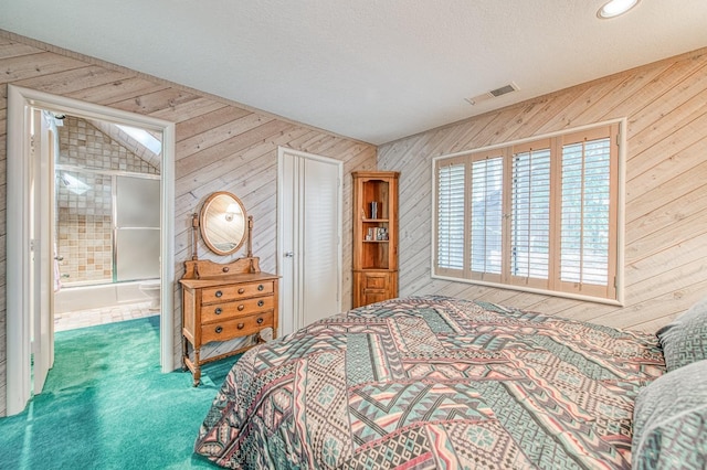 carpeted bedroom featuring connected bathroom, a textured ceiling, and wooden walls