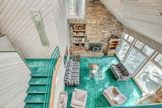 unfurnished living room with high vaulted ceiling, a wood stove, and wooden walls