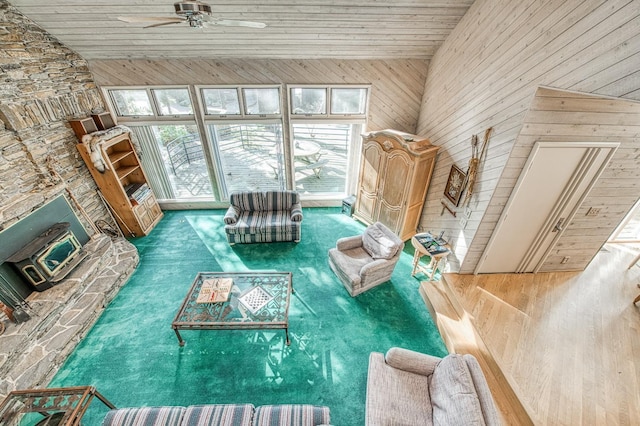 unfurnished living room featuring a healthy amount of sunlight, a wood stove, ceiling fan, and carpet flooring