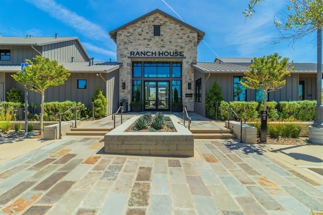 property entrance featuring a standing seam roof, board and batten siding, stone siding, and metal roof