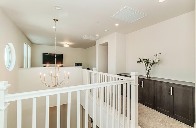 corridor with visible vents, carpet floors, an upstairs landing, recessed lighting, and an inviting chandelier