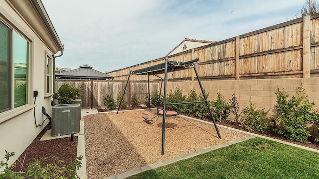 exterior space with cooling unit, a fenced backyard, and a playground