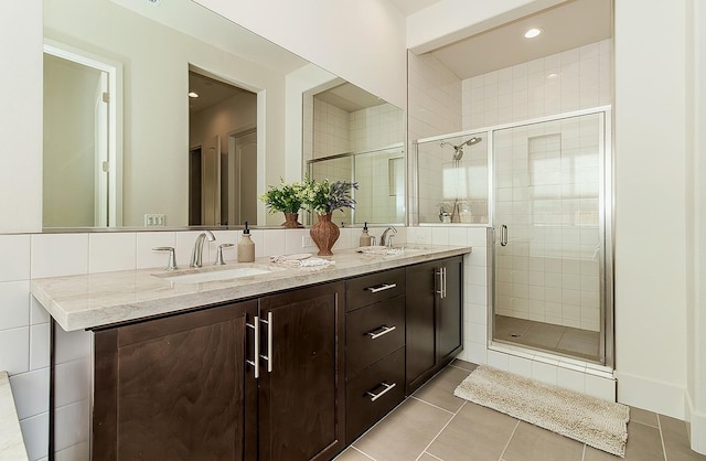 bathroom featuring tile patterned flooring, a shower stall, double vanity, and a sink