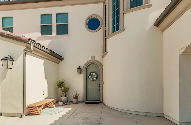 entrance to property with stucco siding and a tile roof