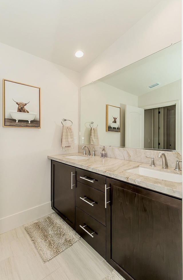 full bath with double vanity, visible vents, baseboards, and a sink