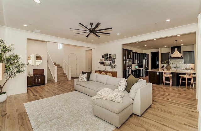 living room with recessed lighting, stairs, light wood-style floors, and ornamental molding