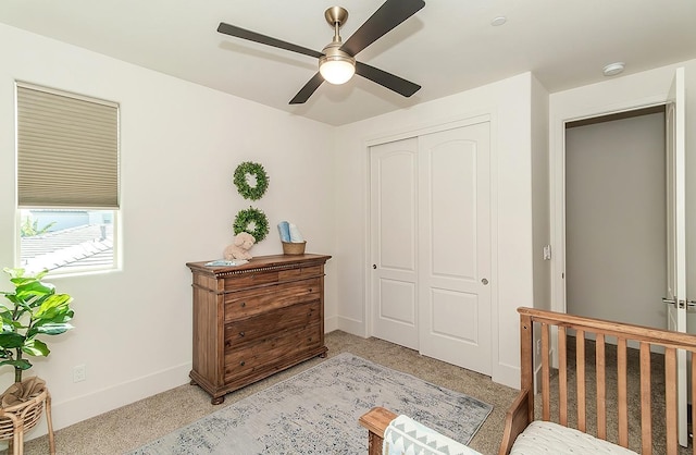 bedroom featuring a closet, light carpet, baseboards, and a ceiling fan