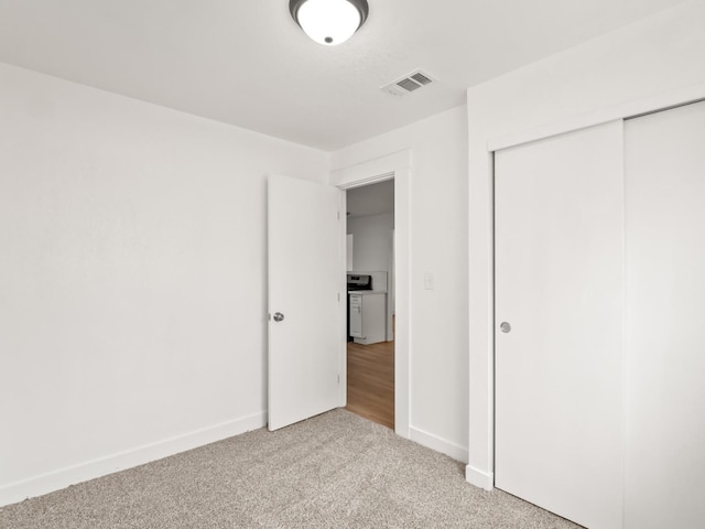 unfurnished bedroom featuring light carpet and a closet