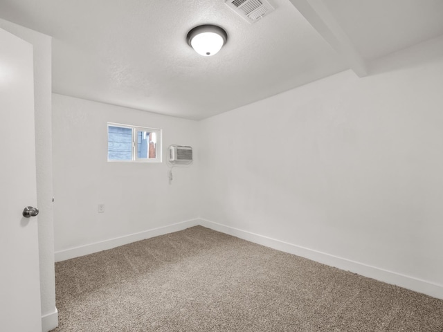 empty room with a wall mounted air conditioner, carpet floors, and a textured ceiling