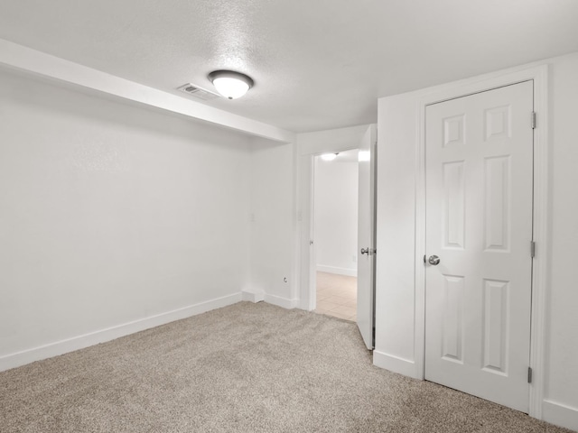 basement featuring light carpet and a textured ceiling