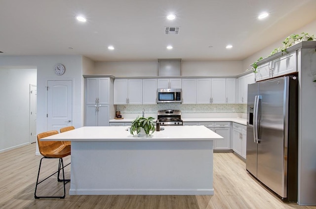 kitchen featuring stainless steel appliances, a kitchen island, a breakfast bar area, and light hardwood / wood-style flooring