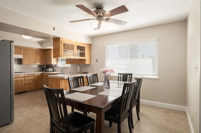 tiled dining room with ceiling fan and a textured ceiling