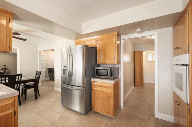 kitchen with tasteful backsplash, light tile patterned floors, stainless steel appliances, and ceiling fan