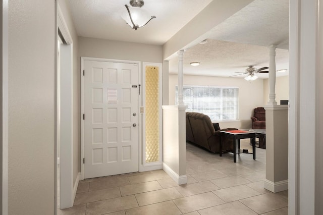 tiled entryway featuring ceiling fan, decorative columns, and a textured ceiling