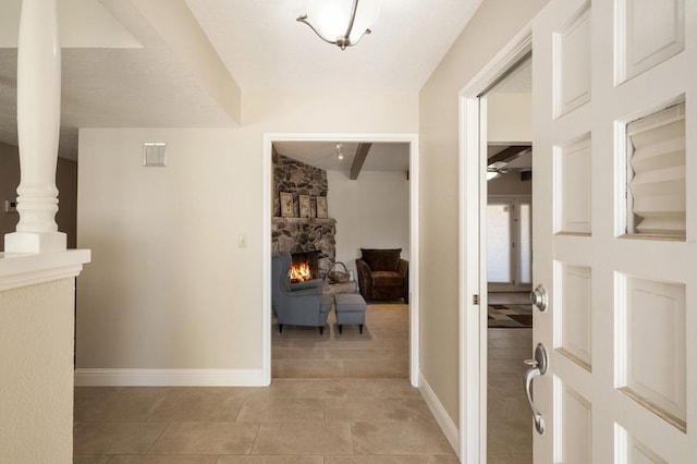 tiled entrance foyer with a stone fireplace and ceiling fan