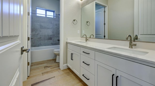 full bathroom featuring vanity, tiled shower / bath combo, and toilet