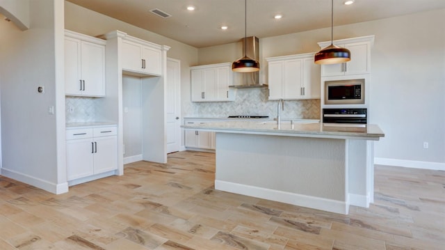 kitchen with black oven, hanging light fixtures, an island with sink, white cabinets, and built in microwave