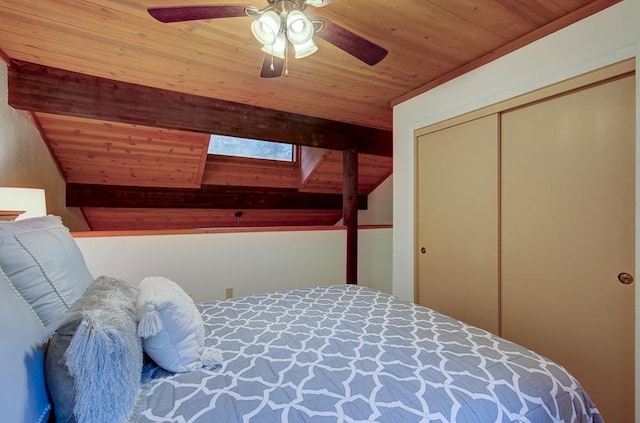 bedroom featuring lofted ceiling with skylight, wooden ceiling, ceiling fan, and a closet