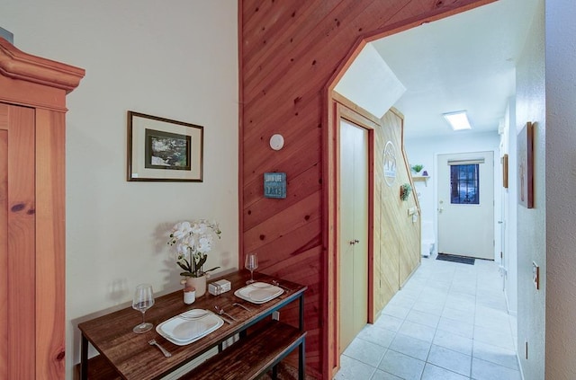 corridor with light tile patterned floors and wood walls