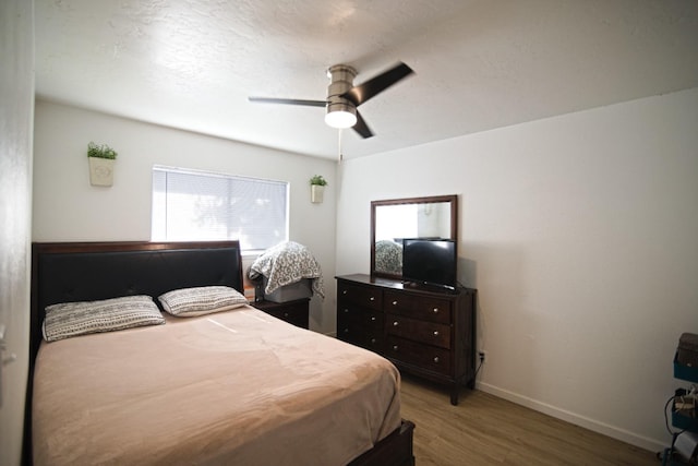 bedroom featuring ceiling fan, baseboards, and wood finished floors