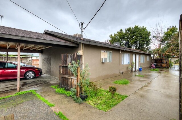 view of side of property with fence, a carport, and stucco siding